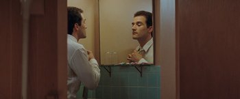 Movie still from “The Adjuster” (1991), directed by Atom Egoyan – A man looking at himself in the mirror in the bathroom; Close Up shot, Over the shoulder angle