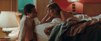 Movie still from “The Adjuster” (1991), directed by Atom Egoyan – A man and a woman sitting on a bed; Medium shot, Low angle