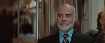 Movie still from “The Adjuster” (1991), directed by Atom Egoyan – An older man wearing a suit and tie; Close Up shot, Low angle