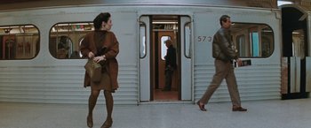 Movie still from “The Adjuster” (1991), directed by Atom Egoyan – A man and a woman walking on a train platform next to each other; Wide shot, High angle