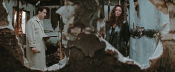 Movie still from “The Adjuster” (1991), directed by Atom Egoyan – A woman standing in front of a tree stump; Medium shot, Low angle