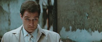 Movie still from “The Adjuster” (1991), directed by Atom Egoyan – A person wearing a suit and tie; Close Up shot, Low angle