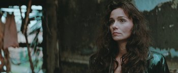 Movie still from “The Adjuster” (1991), directed by Atom Egoyan – A woman with long dark curly hair looking to her left; Close Up shot, Over the shoulder angle