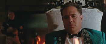 Movie still from “The Adjuster” (1991), directed by Atom Egoyan – A person sitting in a chair near a fire place; Close Up shot, Low angle