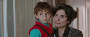Movie still from “The Adjuster” (1991), directed by Atom Egoyan – A woman and a boy pose for a picture; Close Up shot, High angle