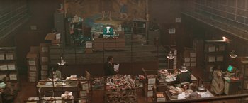 Movie still from “The Adjuster” (1991), directed by Atom Egoyan – A man sitting in front of a bunch of newspapers; Extreme Wide shot, High angle