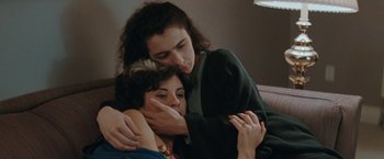 Movie still from “The Adjuster” (1991), directed by Atom Egoyan – Two women are hugging on a couch; Close Up shot, High angle