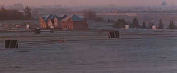 Movie still from “The Adjuster” (1991), directed by Atom Egoyan – An empty field with a soccer goal in the middle of it; Extreme Wide shot, High angle