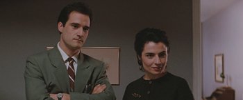 Movie still from “The Adjuster” (1991), directed by Atom Egoyan – A man and a woman standing next to each other in a room; Close Up shot, Low angle