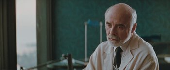 Movie still from “The Adjuster” (1991), directed by Atom Egoyan – An older man sitting in front of microphones in a room; Close Up shot, Low angle