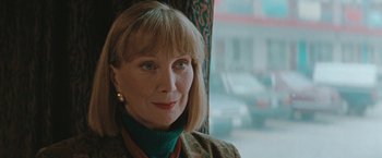 Movie still from “The Adjuster” (1991), directed by Atom Egoyan – A person sitting in a chair near a window; Close Up shot, Low angle