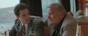 Movie still from “The Adjuster” (1991), directed by Atom Egoyan – Two men sitting next to each other at a table; Close Up shot, Over the shoulder angle