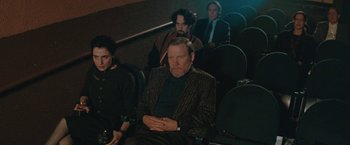 Movie still from “The Adjuster” (1991), directed by Atom Egoyan – A group of people sitting in a theater watching a movie; Medium shot, High angle