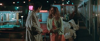 Movie still from “The Adjuster” (1991), directed by Atom Egoyan – Two people talking to each other in front of a restaurant; Medium shot, Over the shoulder angle