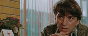 Movie still from “The Adjuster” (1991), directed by Atom Egoyan – A person sitting in front of a window; Close Up shot, Low angle