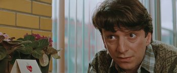 Movie still from “The Adjuster” (1991), directed by Atom Egoyan – A person with short brown hair looking at the camera; Close Up shot, Over the shoulder angle
