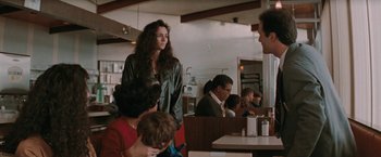Movie still from “The Adjuster” (1991), directed by Atom Egoyan – A group of people sitting at a table in a restaurant; Medium shot, Over the shoulder angle