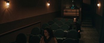 Movie still from “The Adjuster” (1991), directed by Atom Egoyan – A woman is sitting in a movie theater; Wide shot, High angle