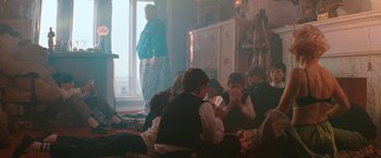 Movie still from “The Adjuster” (1991), directed by Atom Egoyan – A group of people sitting in a living room next to a window; Wide shot, Over the shoulder angle
