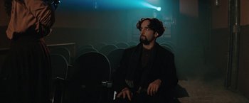 Movie still from “The Adjuster” (1991), directed by Atom Egoyan – A man sitting in an empty theater looking up at the sky; Medium shot, Low angle