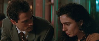 Movie still from “The Adjuster” (1991), directed by Atom Egoyan – A man and a woman sitting next to each other in a room; Close Up shot, Over the shoulder angle