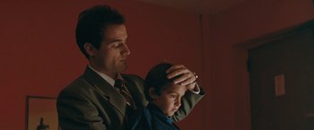 Movie still from “The Adjuster” (1991), directed by Atom Egoyan – A man in a suit and a boy in a blue shirt; Close Up shot, Low angle