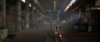 Movie still from “The Adventures of Buckaroo Banzai Across the 8th Dimension” (1984), directed by W.D. Richter – A man riding on the back of an antique car; Extreme Wide shot, High angle