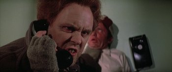 Movie still from “The Adventures of Buckaroo Banzai Across the 8th Dimension” (1984), directed by W.D. Richter – A man with red hair is on the phone and another man with red hair is on the phone; Close Up shot, Low angle