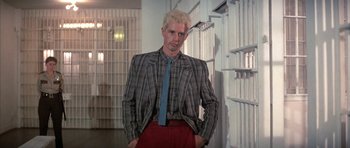 Movie still from “The Adventures of Buckaroo Banzai Across the 8th Dimension” (1984), directed by W.D. Richter – A man with blonde hair wearing a suit and tie; Medium shot, Low angle
