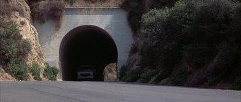 Movie still from “The Adventures of Buckaroo Banzai Across the 8th Dimension” (1984), directed by W.D. Richter – A car is driving through a tunnel on the side of the road; Extreme Wide shot, High angle