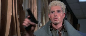 Movie still from “The Adventures of Buckaroo Banzai Across the 8th Dimension” (1984), directed by W.D. Richter – A man holding a gun and looking at the camera; Close Up shot, Low angle