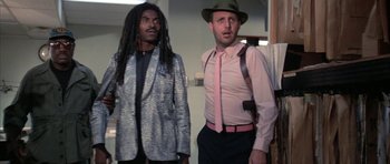 Movie still from “The Adventures of Buckaroo Banzai Across the 8th Dimension” (1984), directed by W.D. Richter – Two men standing next to each other wearing suits and ties; Medium shot, Low angle