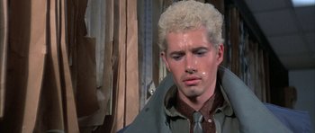 Movie still from “The Adventures of Buckaroo Banzai Across the 8th Dimension” (1984), directed by W.D. Richter – A man with blonde curly hair wearing a green jacket; Close Up shot, Low angle