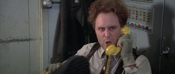 Movie still from “The Adventures of Buckaroo Banzai Across the 8th Dimension” (1984), directed by W.D. Richter – A man holding a yellow phone up to his ear; Close Up shot, Low angle