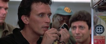 Movie still from “The Adventures of Buckaroo Banzai Across the 8th Dimension” (1984), directed by W.D. Richter – A person using a cell phone; Close Up shot, Low angle