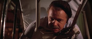 Movie still from “The Adventures of Buckaroo Banzai Across the 8th Dimension” (1984), directed by W.D. Richter – An older man with a mustache is looking at the camera; Close Up shot, Low angle