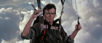 Movie still from “The Adventures of Buckaroo Banzai Across the 8th Dimension” (1984), directed by W.D. Richter – A man in a harness is holding onto some straps; Close Up shot, Low angle
