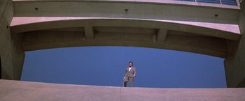 Movie still from “The Adventures of Buckaroo Banzai Across the 8th Dimension” (1984), directed by W.D. Richter – A man in a suit standing under an overpass; Extreme Wide shot, Low angle