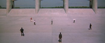 Movie still from “The Adventures of Buckaroo Banzai Across the 8th Dimension” (1984), directed by W.D. Richter – Several skateboarders are on the concrete near a bridge; Extreme Wide shot, High angle