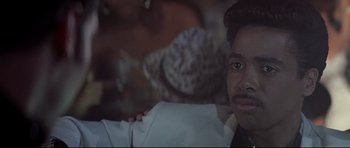 Movie still from “The Adventures of Ford Fairlane” (1990), directed by Renny Harlin – A person wearing a white jacket; Close Up shot, Over the shoulder angle