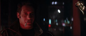 Movie still from “The Adventures of Ford Fairlane” (1990), directed by Renny Harlin – A man smoking a cigarette in a dark room at night; Close Up shot, Over the shoulder angle