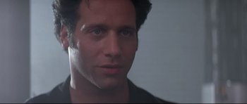 Movie still from “The Adventures of Ford Fairlane” (1990), directed by Renny Harlin – A man's face in a black shirt; Close Up shot, Low angle