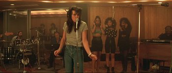 Movie still from “The Adventures of Ford Fairlane” (1990), directed by Renny Harlin – A group of women standing in a room with microphones; Wide shot, Low angle