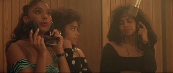 Movie still from “The Adventures of Ford Fairlane” (1990), directed by Renny Harlin – A group of people that are sitting in a room together; Medium shot, Low angle