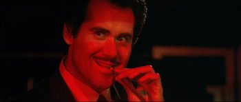 Movie still from “The Adventures of Ford Fairlane” (1990), directed by Renny Harlin – A person with a red light in the background; Close Up shot, Low angle