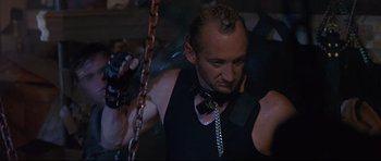Movie still from “The Adventures of Ford Fairlane” (1990), directed by Renny Harlin – A man in a black tank top holding onto a chain; Close Up shot, Low angle