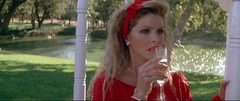 Movie still from “The Adventures of Ford Fairlane” (1990), directed by Renny Harlin – A woman in a red dress holding a glass of wine; Close Up shot, Over the shoulder angle