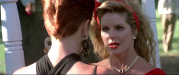 Movie still from “The Adventures of Ford Fairlane” (1990), directed by Renny Harlin – A woman with a red bow in her hair and a woman with red lipstick; Close Up shot, Over the shoulder angle
