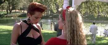 Movie still from “The Adventures of Ford Fairlane” (1990), directed by Renny Harlin – Two women are talking to each other in a park; Medium shot, Over the shoulder angle