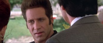 Movie still from “The Adventures of Ford Fairlane” (1990), directed by Renny Harlin – A person wearing a suit and tie; Close Up shot, Over the shoulder angle